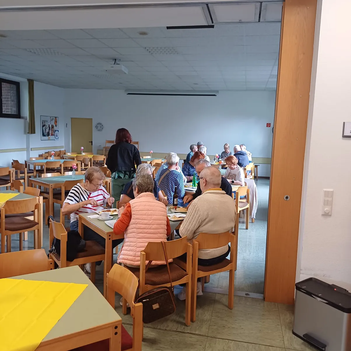 Ein Blick in den großen Innenraum mit einigen Sommergästen, die es sich bei Essen, Trinken und angenehmer Gesellschaft gut gehen lassen. Die Tische stehen in Gruppen und sind hübsch dekoriert.