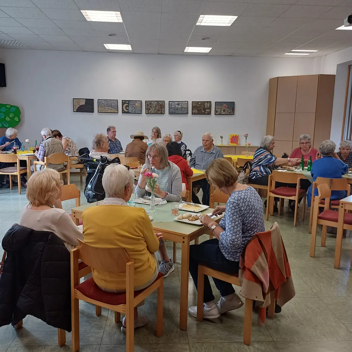Der Blick in den Vorderen Innenraum. Gefüllt mit gedeckten, in Gruppen aufgestellten Tischen und Stühlen, wo sich die Gäste hinsetzen können, um zu Essen und Trinken und vor allen auf die Gesellschaft der anderen Genießen können.